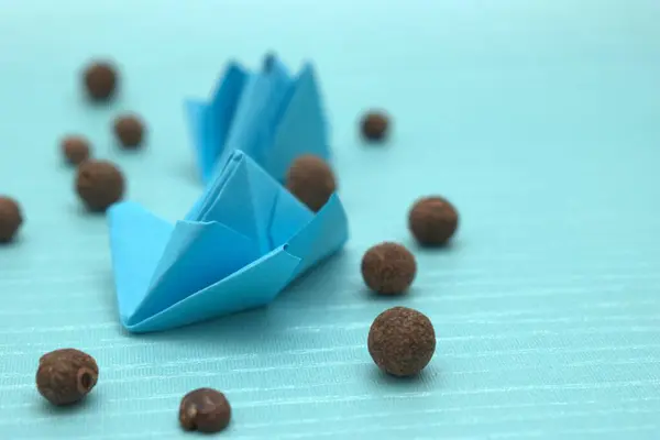 Ahşap bir arka planda mavi origami kağıt gemisinin yakın çekimi.