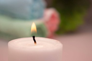 Yumuşak rulo havlular ve arka planda pastel çiçeklerle düzenlenmiş koyu renk spa taşları. Sıcak bej ayarı sakin ve huzurlu bir ortam yaratır. Sağlık, kaplıca ya da meditasyon için mükemmel..