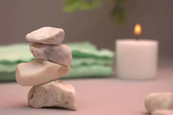 Yumuşak rulo havlular ve arka planda pastel çiçeklerle düzenlenmiş koyu renk spa taşları. Sıcak bej ayarı sakin ve huzurlu bir ortam yaratır. Sağlık, kaplıca ya da meditasyon için mükemmel..