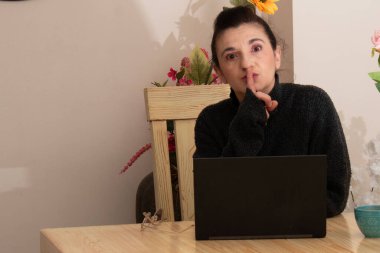 Mujer usando su computador porttil en casa, interactuando con la cmara en distintas actitudes: atencin, risa, saludo.