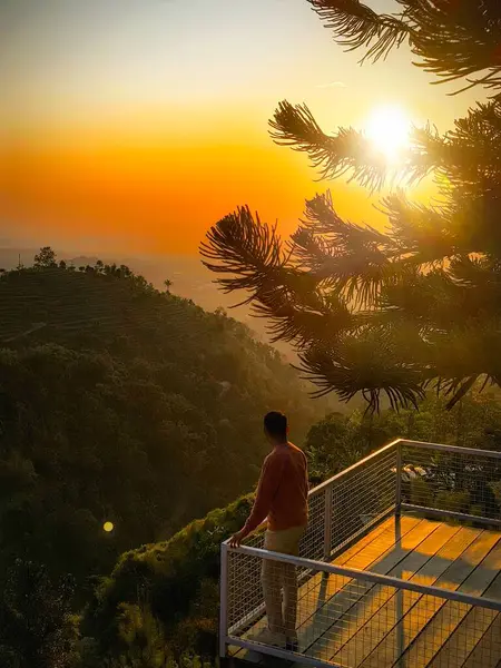 Otelin terasında gün doğumu manzaralı bir adam.