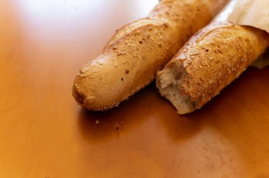 Tahta masada iki Fransız ekmeği. Pasta dükkanında taze hamur işleri. Ekmek pişiriyorum. Restoran menüsünde Fransız mutfağı. Öğle yemeği vakti. Ekmek için kağıt paketleme.