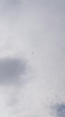 Arka planda dağınık bulutlarla gökyüzünde uçan küçük bir uçak.