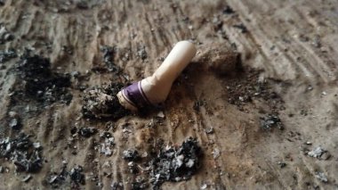 Used cigarette butt on rough surface with ash