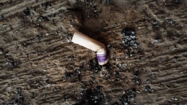 Used cigarette butt on rough surface with ash