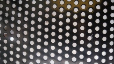 Eşit aralıklı yuvarlak delikli delinmiş metal bir levhanın yakın çekimi
