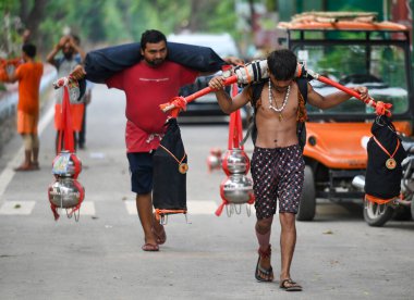 NOIDA, INDIA - JULY 25, 2024: Kanwariya carries holy water collected from Ganga River in Haridwar during Kanwar Yatra at Sector 14A on July 25, 2024 in Noida, India. The Gautam Budh Nagar administration is on its toes to ensure proper arrangements  clipart