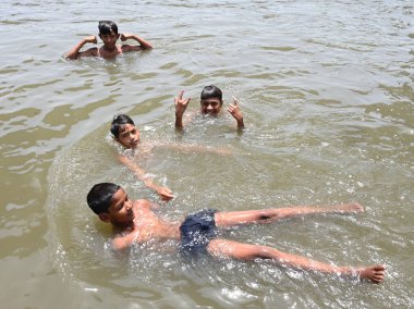 NEW DELHI, INDIA - 30 Mayıs 2024 Perşembe günü Doğu Delhi 'de Ghazipur drenajı' nda erkekler serinliyor.. 