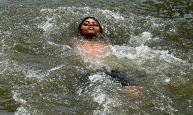 NEW DELHI, INDIA - 30 Mayıs 2024: Bir çocuk 30 Mayıs 2024 Perşembe günü Doğu Delhi 'de Ghazipur drenajında serinliyor.. 