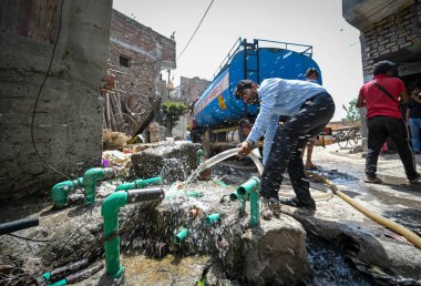 NEW DELHI, INDIA - 30 Mayıs 2024: 30 Mayıs 2024 'te Yeni Delhi, Hindistan' da Anand Parbat 'ta su krizi sırasında Delhi Jal Tahta Tankeri' nden su dolduran insanlar görüldü