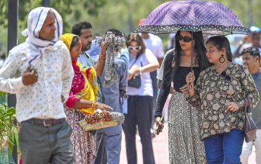 Hindistan Kapısı yakınlarındaki sıcak bir günde, 30 Mayıs 2024 'te Delhi-NCR sıcaklığı artarken, turistler kendilerini Atkı ve şemsiye altında koruyorlar.. 