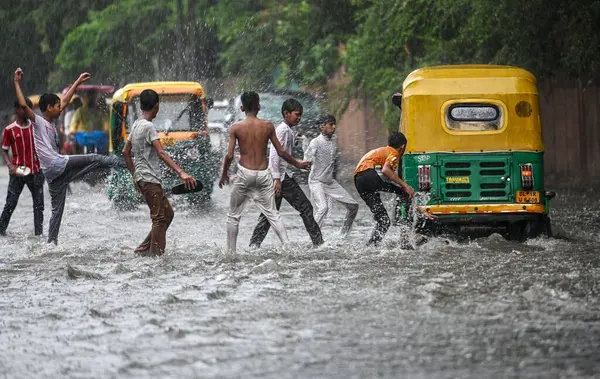 NEW DELHI, INDIA - 27 Temmuz 2024 'te, Hindistan' ın Yeni Delhi kentinde, 27 Temmuz 2024 'te, şehir merkezi yakınlarındaki su dolu bir Tagore Yolu' nda oynayan çocuklar. 