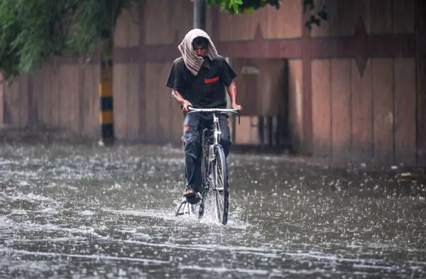 NEW DELHI, INDIA - 27 HAZİRAN: 27 Temmuz 2024 tarihinde Hindistan 'ın Yeni Delhi kentinde, kısa bir yağmur döneminden sonra, şehir merkezi yakınlarındaki Tagore Yolu' nda su dolmuş bir adam