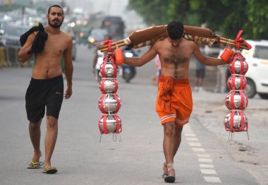 GURUGRAM, INDIA - 26 Temmuz 2024: Haridwar 'daki Ganga Nehri' nden toplanan kutsal suyu taşıyan Kanwariyas, Kanwar Yatra sırasında Signature Towre Chowk yakınlarındaki Ulusal Otoyol 48 'e geri dönüyor.