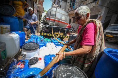 NEW DELHI, INDIA - 30 Mayıs 2024: 30 Mayıs 2024 'te Yeni Delhi, Hindistan' da Anand Parbat 'ta su krizi sırasında Delhi Jal Tahta Tankeri' nden su dolduran insanlar görüldü