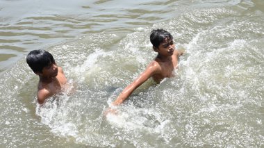 NEW DELHI, INDIA - 30 Mayıs 2024 Perşembe günü Doğu Delhi 'de Ghazipur drenajı' nda erkekler serinliyor.. 