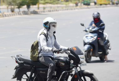 GURUGRAM, INDIA - MAY 20: A commuter covering face with cloth to protect from heat wave on a hot summer day at MDI Chowk on May 20, 2024 in Gurugram, India.  clipart