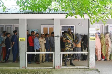SRINAGAR, INDIA - 25 Mayıs 2024: İnsanlar Srinagar 'ın güneyindeki Srigufwara bölgesinde yapılan Lok Sabha seçimlerinin altıncı safhasında, 25 Mayıs 2024' te Hindistan 'ın Srinagar kentinde oy kullanmak için sırada bekliyorlar..