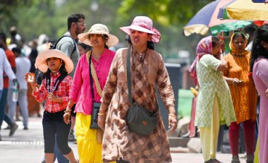 Hindistan Kapısı yakınlarındaki sıcak bir günde, 30 Mayıs 2024 'te Delhi-NCR sıcaklığı artarken, turistler kendilerini Atkı ve şemsiye altında koruyorlar.. 