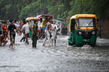 NEW DELHI, INDIA - 27 Temmuz 2024 'te, Hindistan' ın Yeni Delhi kentinde, 27 Temmuz 2024 'te, şehir merkezi yakınlarındaki su dolu bir Tagore Yolu' nda oynayan çocuklar. 