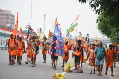 GURUGRAM, INDIA - 26 Temmuz 2024: Haridwar 'daki Ganga Nehri' nden toplanan kutsal suyu taşıyan Kanwariyas, Kanwar Yatra sırasında Signature Towre Chowk yakınlarındaki Ulusal Otoyol 48 'e geri dönüyor.