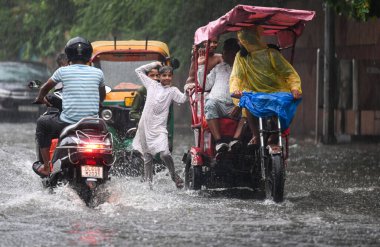 NEW DELHI, INDIA - 27 Temmuz 2024 'te, Hindistan' ın Yeni Delhi kentinde, 27 Temmuz 2024 'te, şehir merkezi yakınlarındaki su dolu bir Tagore Yolu' nda oynayan çocuklar. 