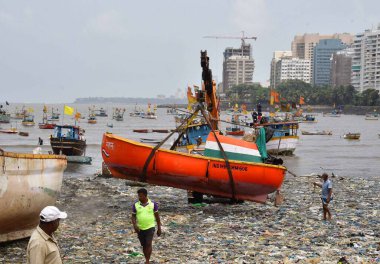 MUMBAI, INDIA - 27 Mayıs 2024 'te Hindistan' ın Mumbai kentindeki Badhwar Park 'ta, bir vinç kullanılarak deniz kıyısından çıkarılan bir tekne..
