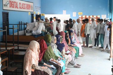 GURUGRAM, INDIA - 25 Mayıs 2024 'te Hindistan' ın Gurugram kentindeki Ghasera köyünde yapılan Lok Sabha seçimlerinin altıncı safhasında oy kullanmak için sandık kulübesinin önünde bekleyenler. 