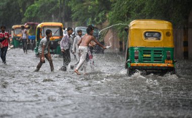 NEW DELHI, INDIA - 27 Temmuz 2024 'te, Hindistan' ın Yeni Delhi kentinde, 27 Temmuz 2024 'te, şehir merkezi yakınlarındaki su dolu bir Tagore Yolu' nda oynayan çocuklar. 