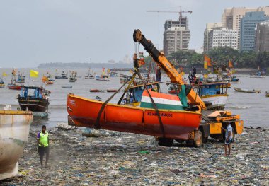 MUMBAI, INDIA - 27 Mayıs 2024 'te Hindistan' ın Mumbai kentindeki Badhwar Park 'ta, bir vinç kullanılarak deniz kıyısından çıkarılan bir tekne..