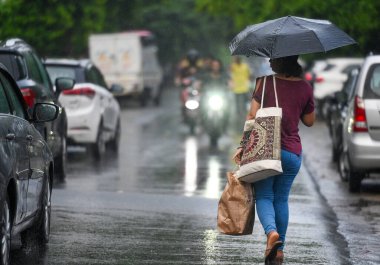 27 Temmuz 2024 'te, nemli bir yaz sonrasında, Hindistan' ın Noida kentinde akşam yağmuru sırasında dışarı çıkan banliyö sakinleri. 