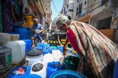 NEW DELHI, INDIA - 30 Mayıs 2024: 30 Mayıs 2024 'te Yeni Delhi, Hindistan' da Anand Parbat 'ta su krizi sırasında Delhi Jal Tahta Tankeri' nden su dolduran insanlar görüldü