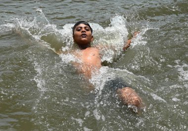 NEW DELHI, INDIA - 30 Mayıs 2024: Doğu Delhi 'de Ghazipur drenajında serinleyen bir çocuk 30 Mayıs 2024 Perşembe günü yükseldi. Delhi 'de kavurucu sıcaklıklar yaşanıyor. Şehrin belli kısımları neredeyse 44 dereceye ulaşıyor..