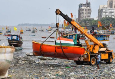 MUMBAI, INDIA - 27 Mayıs 2024 'te Hindistan' ın Mumbai kentindeki Badhwar Park 'ta, bir vinç kullanılarak deniz kıyısından çıkarılan bir tekne..