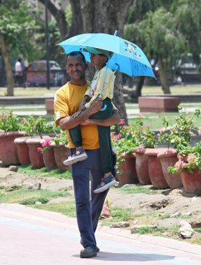 NEW DELHI, INDIA - 20 Mayıs 2024: Sıcak yaz mevsiminde Yeni Delhi, Hindistan 'da 20 Mayıs 2024 tarihinde Kartvaya Yolu çimlerinde sıcak hava dalgasına göğüs geren ziyaretçiler. Hindistan Meteoroloji Bölümü (IMD) hava durumu raporunda şiddetli sıcak hava dalgası koşulları belirtiliyor