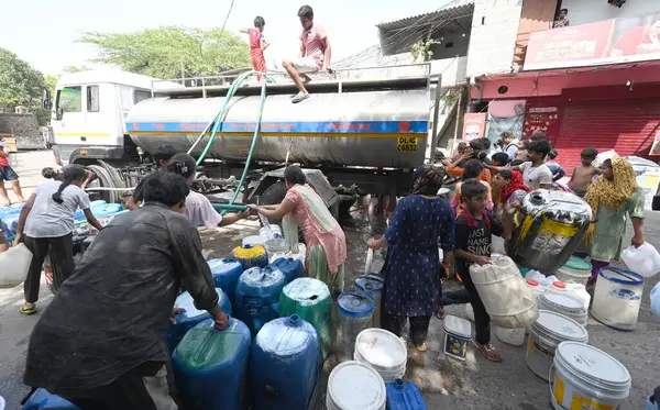 NEW DELHI, INDIA - 29 Mayıs 2024 'te Hindistan' ın Yeni Delhi kentindeki Sanjay Camp Chanakyapuri 'de yaz aylarında yaşanan bir su krizi sırasında, yerliler bir tankerden içme suyu alıyorlar. Artan sıcaklıkla Delhi büyük bir su kriziyle karşı karşıya.