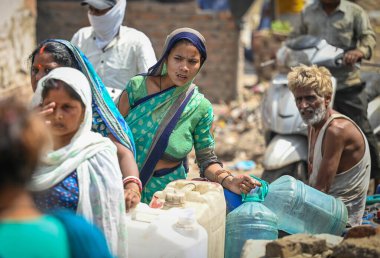 NEW DELHI, INDIA - 30 Mayıs 2024: 30 Mayıs 2024 'te Yeni Delhi, Hindistan' da Anand Parbat 'ta su krizi sırasında Delhi Jal Tahta Tankeri' nden su dolduran insanlar görüldü