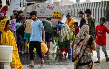 NEW DELHI, INDIA - MAY 22, 2024: Residents and children fill water from a Delhi Jal Board (DJB) water tanker at NH-24 near Kalyanpuri area, on May 22, 2024 in New Delhi, India. clipart