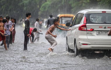 NEW DELHI, INDIA - 27 Temmuz 2024 'te, Hindistan' ın Yeni Delhi kentinde, 27 Temmuz 2024 'te, şehir merkezi yakınlarındaki su dolu bir Tagore Yolu' nda oynayan çocuklar. 