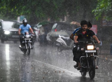 27 Temmuz 2024 'te, nemli bir yaz sonrasında, Hindistan' ın Noida kentinde akşam yağmuru sırasında dışarı çıkan banliyö sakinleri. 