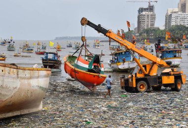 MUMBAI, INDIA - 27 Mayıs 2024 'te Hindistan' ın Mumbai kentindeki Badhwar Park 'ta, bir vinç kullanılarak deniz kıyısından çıkarılan bir tekne..