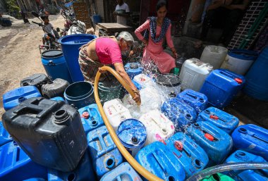 NEW DELHI, INDIA - 30 Mayıs 2024: 30 Mayıs 2024 'te Yeni Delhi, Hindistan' da Anand Parbat 'ta su krizi sırasında Delhi Jal Tahta Tankeri' nden su dolduran insanlar görüldü