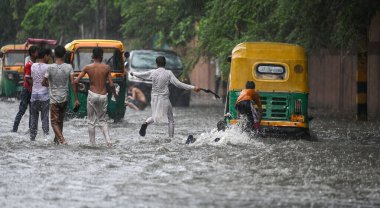 NEW DELHI, INDIA - 27 Temmuz 2024 'te, Hindistan' ın Yeni Delhi kentinde, 27 Temmuz 2024 'te, şehir merkezi yakınlarındaki su dolu bir Tagore Yolu' nda oynayan çocuklar. 