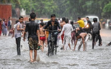 NEW DELHI, INDIA - 27 Temmuz 2024 'te, Hindistan' ın Yeni Delhi kentinde, 27 Temmuz 2024 'te, şehir merkezi yakınlarındaki su dolu bir Tagore Yolu' nda oynayan çocuklar. 