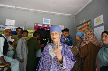SRINAGAR, INDIA - 25 Mayıs 2024: Srinagar 'ın güneyindeki Srigufwara bölgesinde yapılan Lok Sabha seçimlerinin altıncı safhasında bir kadın, 25 Mayıs 2024' te Srinagar 'da oy kullandıktan sonra işaretli parmağını gösterdi