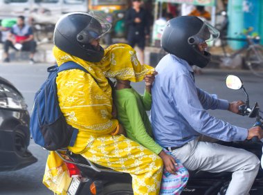 19 Mayıs 2024 'te Hindistan' ın Gurugram kentinde, Rajiv Chowk yakınlarında bir yaz öğleden sonra yol boyunca yol alırken, insanlar sıcaktan korunmak için yüzlerini kıyafetle örtüyorlar..