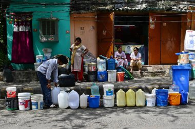 NEW DELHI, INDIA - MAY 29, 2024: Residents of JJ Cluster Vivekanand Colony at Chanakyapuri fill up water from a tanker in the morning on May 29, 2024 in New Delhi, India.  clipart