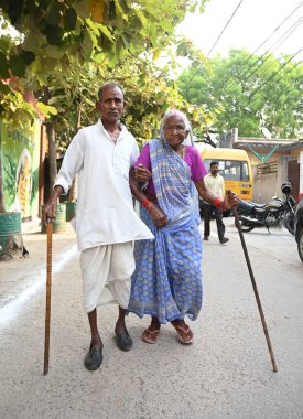 LUCKnow, INDIA - 20 Mayıs 2024 'te Hindistan' ın Lucknow kentinde yapılan Lok Sabha seçimlerinin beşinci safhasında Central Academy oy kullanma merkezinde oy kullanmadan önce yaşlı bir çift kimlik kartını gösteriyor.. 