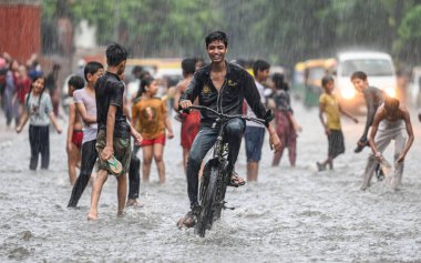 NEW DELHI, INDIA - 27 Temmuz 2024 'te, Hindistan' ın Yeni Delhi kentinde, 27 Temmuz 2024 'te, şehir merkezi yakınlarındaki su dolu bir Tagore Yolu' nda oynayan çocuklar. 