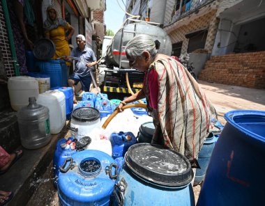 NEW DELHI, INDIA - 30 Mayıs 2024: 30 Mayıs 2024 'te Yeni Delhi, Hindistan' da Anand Parbat 'ta su krizi sırasında Delhi Jal Tahta Tankeri' nden su dolduran insanlar görüldü